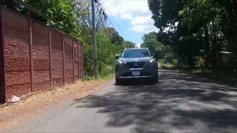 Nissan-X-Trail-Conduciendo-Por-La-Calle-Entre-árboles,-SUV-Crossover-Compacto,-Alinearse