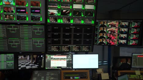 Dolly-to-left-of-monitoring-control-tv-screens-in-television-broadcast-centre
