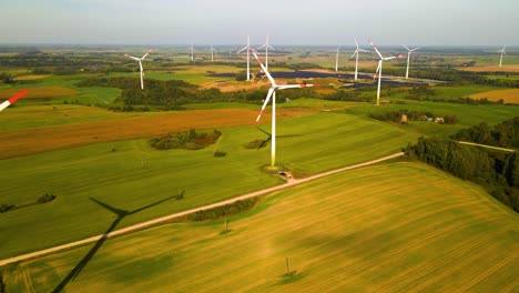 Drohnenaufnahmen-Von-Windkraftanlagen-In-Einem-Windpark,-Der-An-Einem-Sonnigen-Tag-Auf-Einem-Weiten-Grünen-Feld-In-Taurage,-Litauen,-Grüne-Elektrische-Energie-Erzeugt