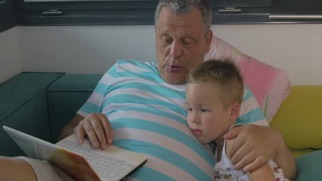 Child-and-grandfather-using-laptop-at-home