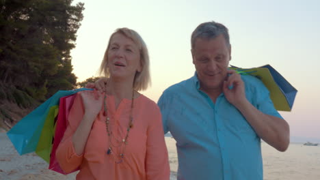 Mature-couple-relaxing-with-seaside-walk-after-shopping