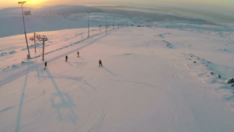 Aerial-view-of-skiers-and-snowboarders-at-sunset