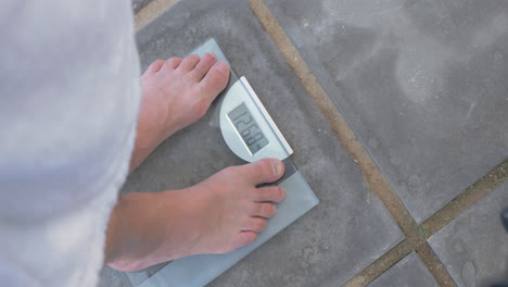 Man-weighing-himself-on-bathroom-scales