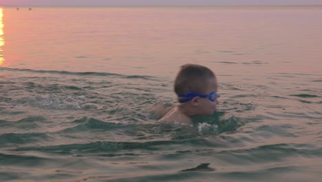 Boy-in-goggles-learning-to-swim-with-his-mother