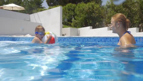 Mother-and-son-playing-with-ball-in-the-pool
