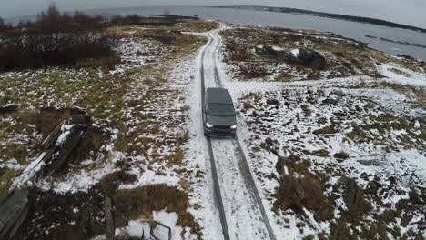 Aerial-view-of-car-driving-away-from-shore-in-winter