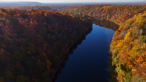 An-aerial-view-high-over-a-lake-on-a-sunny-day-with-colorful-fall-trees
