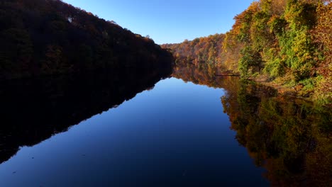 Eine-Luftaufnahme-Eines-Spiegelähnlichen-Sees-An-Einem-Sonnigen-Tag-Mit-Bunten-Herbstbäumen