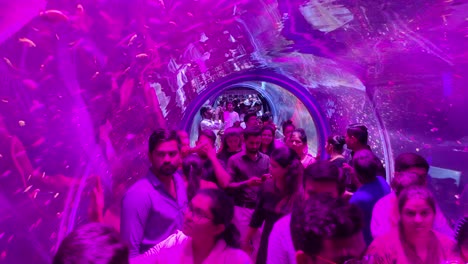 Fish-aquarium-with-pink-light,-people-watching-fish-in-underwater-tunnel