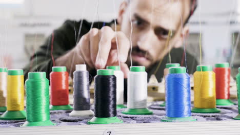 Man-in-a-fabric-factory-checking-the-sewing-thread