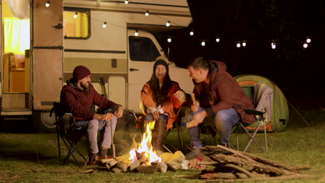 Group-of-close-friends-laughing-together-around-camp-fire