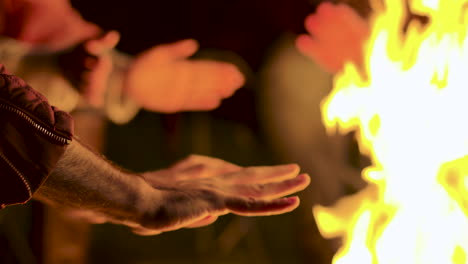 Close-up-of-man-warming-up-his-hands-at-camp-fire