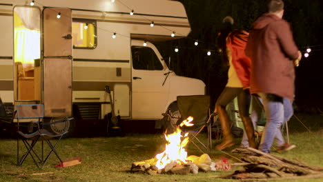Group-of-close-friends-dancing-around-camp-fire-in-a-cold-night-of-autumn