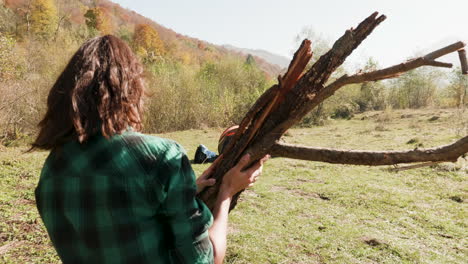 Follow-shot-of-young-woman-with-wood-for-camp-fire
