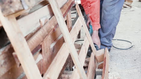 Man-using-electric-saw-to-cut-wooden-pallets