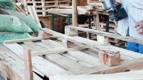 Man-in-a-warehouse-using-a-nail-gun-for-wooden-pallets