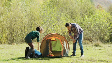 Schöne-Frau-Hilft-Ihrem-Mann-Beim-Aufbau-Des-Campingzeltes