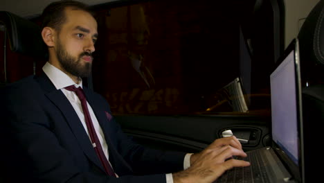 Successful-businessman-typing-on-his-laptop-on-the-backseat-of-his-limousine