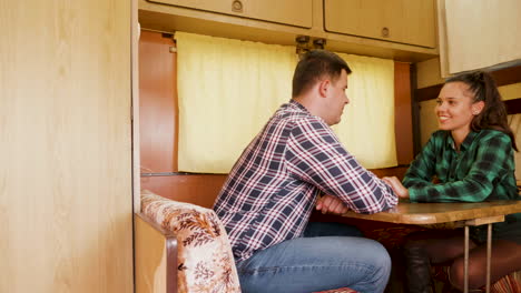Couple-laughing-together-and-holding-hands-inside-of-retro-camper-van