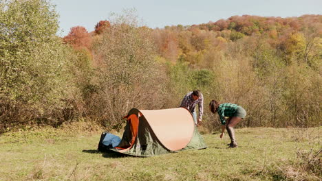 Schönes-Junges-Paar-Hilft-Sich-Gegenseitig-Beim-Aufbau-Des-Campingzeltes