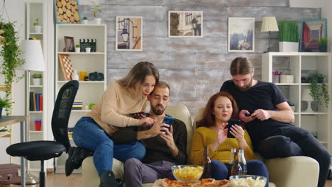 Gruppe-Von-Freunden,-Die-Auf-Der-Couch-Sitzen-Und-Ihre-Smartphones-Benutzen