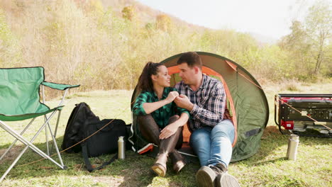 Attractive-young-couple-cuddling-in-comfortable-camping-site