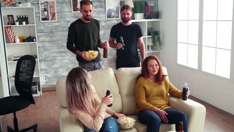 Young-man-giving-chips-to-his-friends-while-watching-a-tv-show