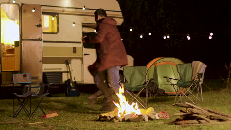 Cheerful-young-couple-dancing-around-camp-fire-in-cold-night-of-autumn