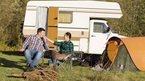 Hipster-boyfriend-kissing-his-girlfriend-hand-while-sitting-on-camping-seats