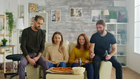 Group-of-friends-sitting-on-couch-reaching-out-for-pizza