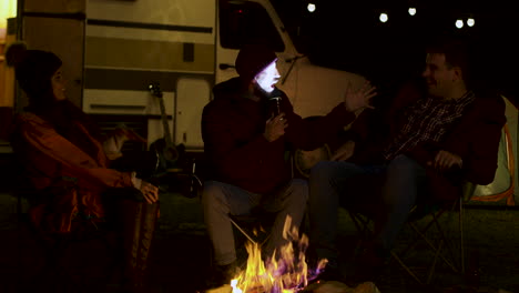 Bearded-man-telling-a-scary-story-to-his-friends-around-camp-fire