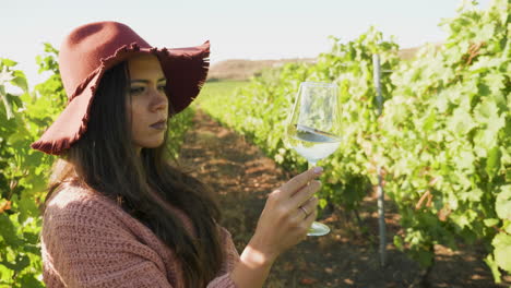 Woman-in-a-vineyard-looking-at-a-glass-of-wine