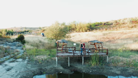 Inlove-couple-spending-a-romantic-evening-on-a-pontoon-in-a-rural-area