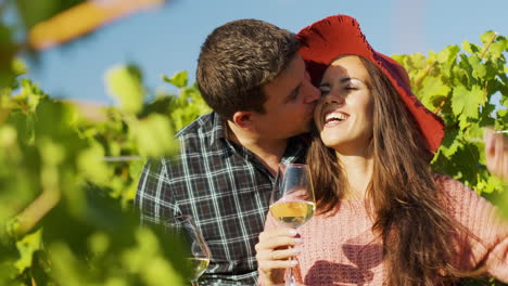 Close-up-of-couple-embracing-each-other-while-holding-glasses-of-wine-in-hands