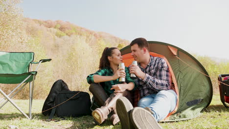 Couple-enjoying-a-drink-together-in-front-of-their-camping-tent