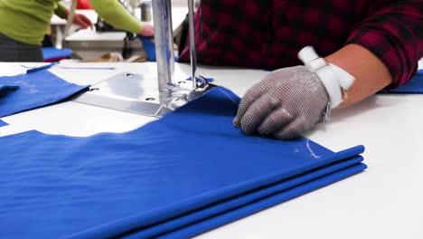 Trabajadora-Con-Un-Cuchillo-Eléctrico-Cortando-Tela-En-Una-Fábrica-Textil