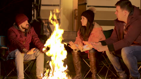 Handheld-footage-of-friends-warming-their-hand-at-camp-fire-in-a-cold-autumn-night