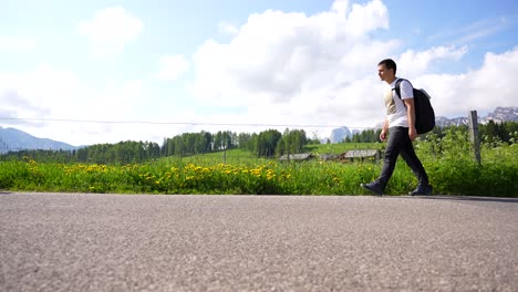 Man-walking-on-an-asphalted-road-in-green-Alpe-di-Siusi,-Italy