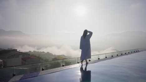 Woman-walking-by-the-side-of-the-pool-in-the-morning-at-luxury-hotel