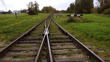 POV-of-fly-over-train-railway-road-tracks-with-grass,-rock-on-a-bright-fall-day