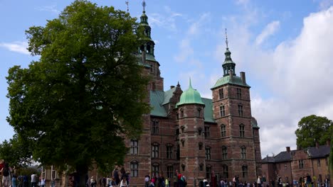 Sunny-day-at-Rosenborg-Castle-surrounded-by-tourists-next-to-grand-tree,-Copenhagen