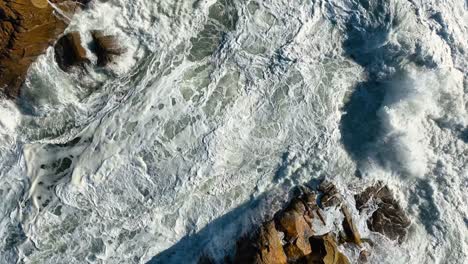 White-Foamy-Sea-Waves-Splashing-Against-Rocks-In-Summer,-Carballo,-A-Coruña,-Spain---aerial-top