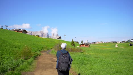 Man-with-cap-adjusts-his-backpack-to-start-hiking-route-in-Alpe-di-Siusi,-Dolomites,-Italy