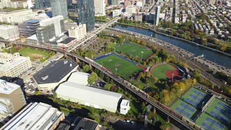 Aerial-tilt-shot-of-the-skyline-and-the-Penn-Athletics-Facilities,-fall-day-in-Philadelphia