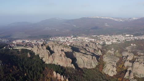 Strafing-from-the-righ-to-the-left-to-show-a-more-panoramic-view-of-the-Belogradchik-sculptural-rocks,-the-town,-ane-the-Balkan-mountain-ranges-in-the-background-in-Vidin-province-in-Bulgaria