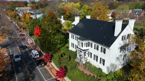 White-colonial-house-surrounded-by-fall-foliage-in-small-town-America