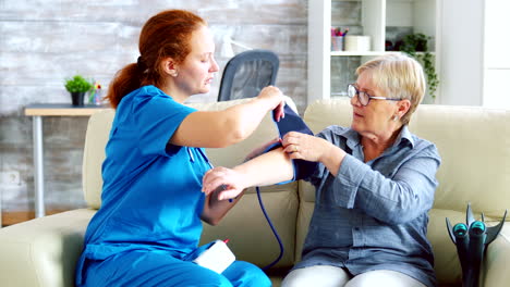 Female-doctor-taking-blood-pressure-of-senior-woman