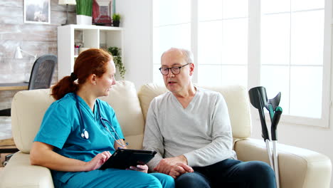 Female-caucasian-nurse-taking-notes-about-elderly-man-health-in-bright-and-cozy-nursing-home
