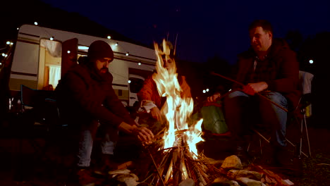 Freunde-Machen-Das-Campingfeuer-Stärker,-Um-Sich-Aufzuwärmen