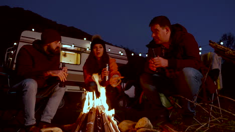 Caucasian-friend-enjoying-a-beer-together-in-front-of-their-retro-camper